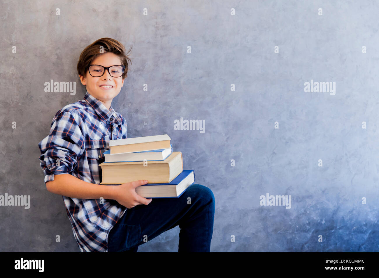 Cute teenage school boy holding books against wall Stock Photo - Alamy