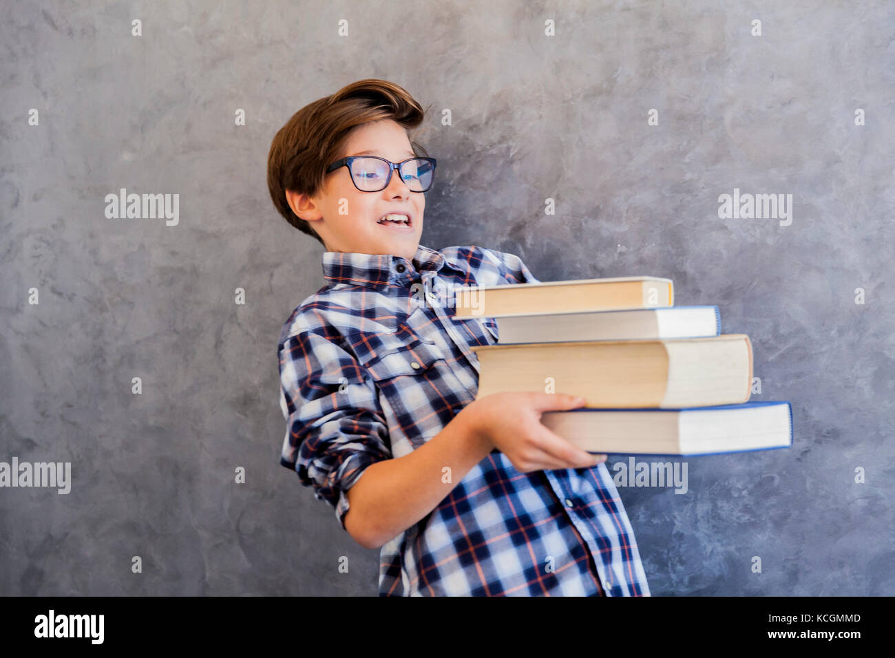 Cute teenage school boy holding books against wall Stock Photo - Alamy