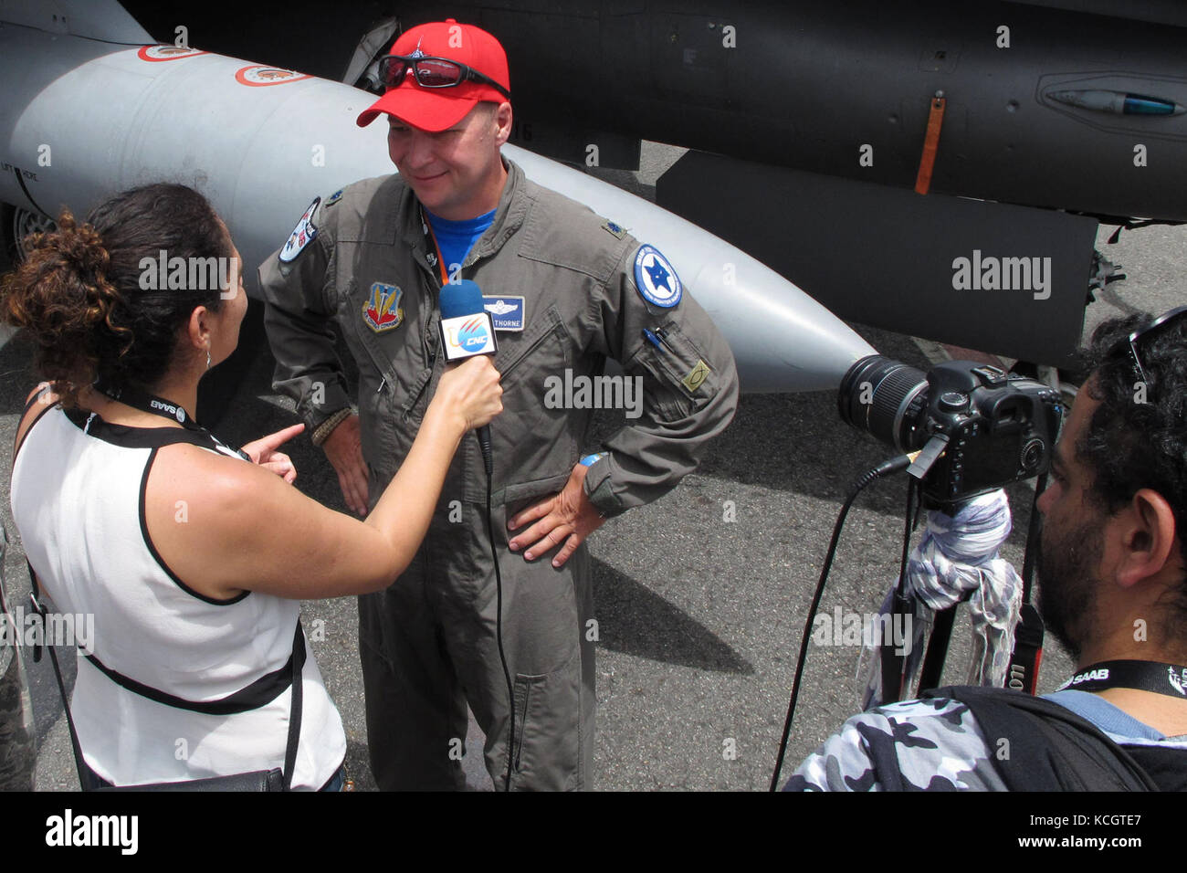A reporter from a Colombian television station interviews U.S. Air Force Lt. Col. Andrew Thorne while Tech. Sgt. Jorge Intriago translates into Spanish in front of a South Carolina Air National Guard F-16 during the Colombian Air Force’s Feria Aeronautica Internaccional – Colombia in Rionegro, July 14, 2017. The United States Air Force is participating in the four-day air show with two South Carolina Air National Guard F-16s as static displays, plus static displays of a KC-135, KC-10, along with an aerial demonstration by the Air Combat Command’s Viper East Demo Team and a B-52 flyover. The Un Stock Photo