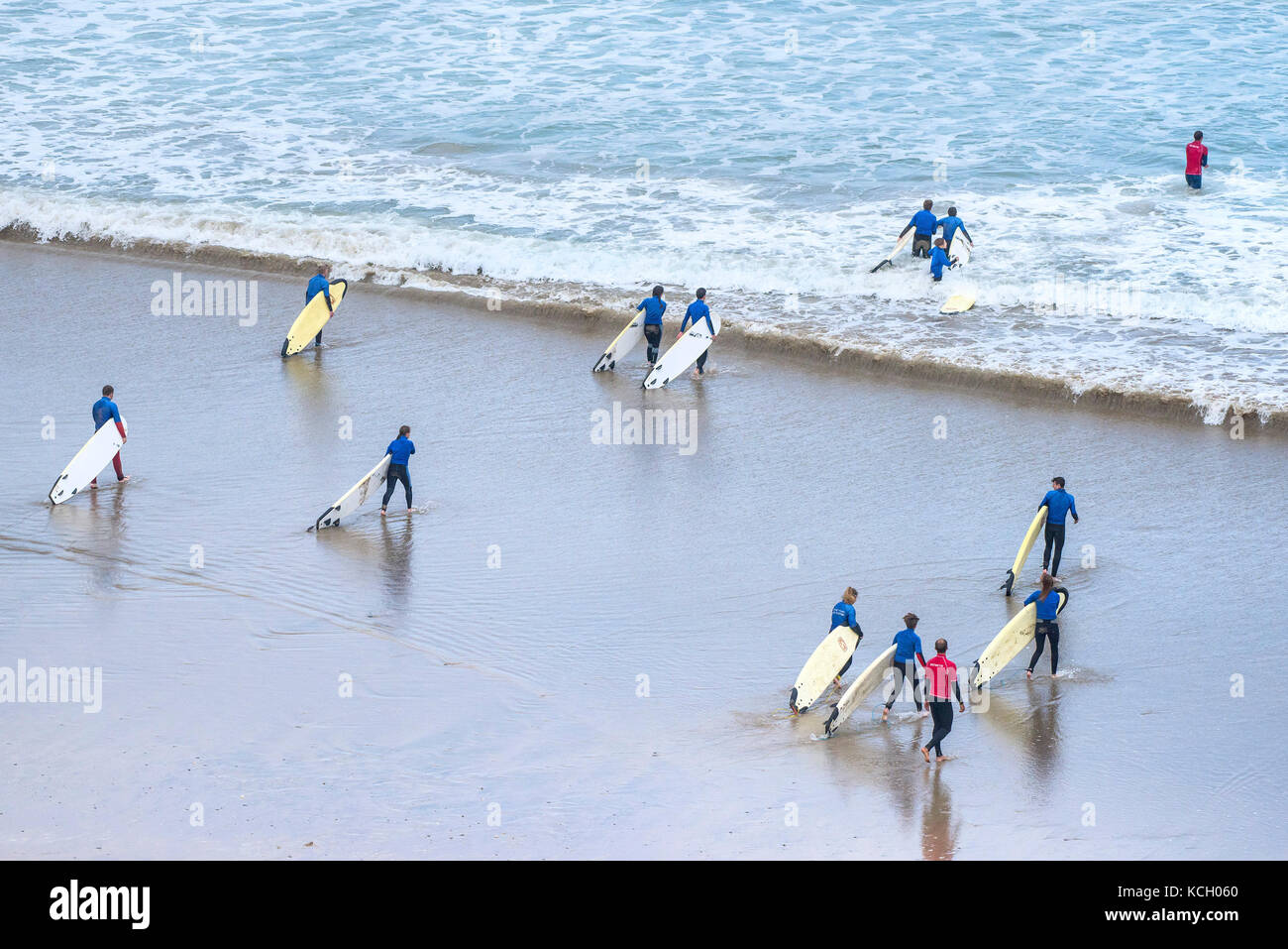 Surfing in the UK.  Young people carrying their surfboards at the start of their surf lesson. Cornwall Stock Photo