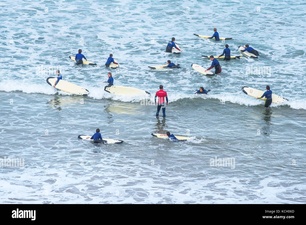 Surfing in Cornwall UK - young people enjoying learning how to surf with help from a surfing instructor. Stock Photo