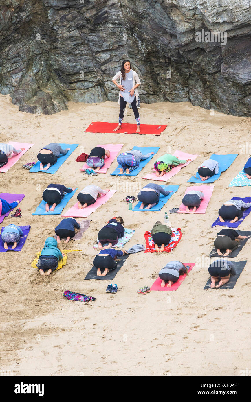A womens group practising yoga on a beach - Surf Betty’s Festival a festival held in Newquay empowering women through fitness and surfing. Cornwall. Stock Photo