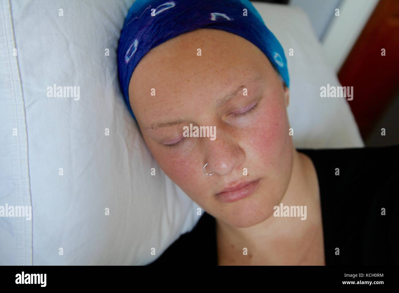 Young cancer patient in a headscarf sleeping in bed Stock Photo