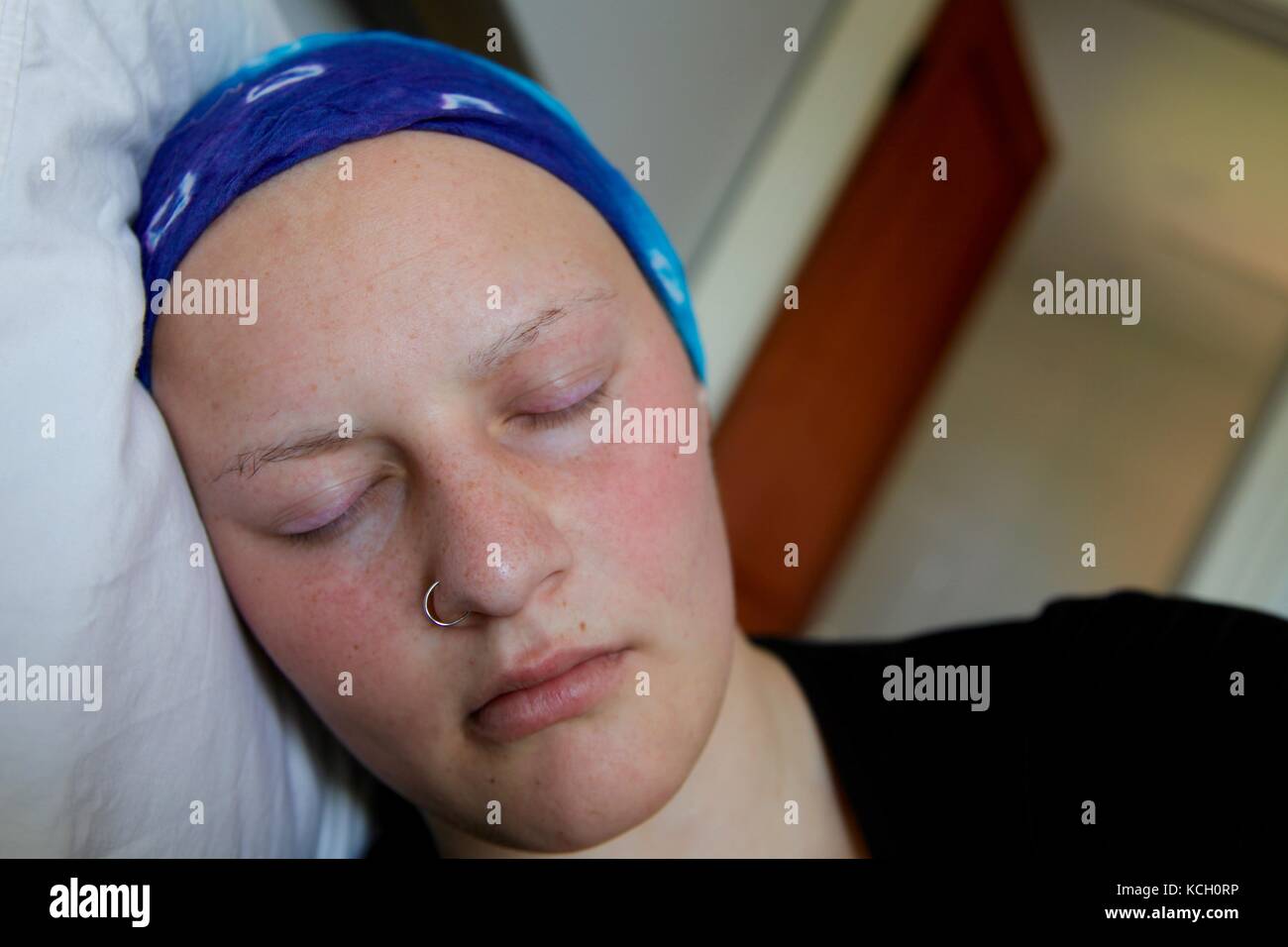 Young cancer patient in a headscarf sleeping in bed Stock Photo