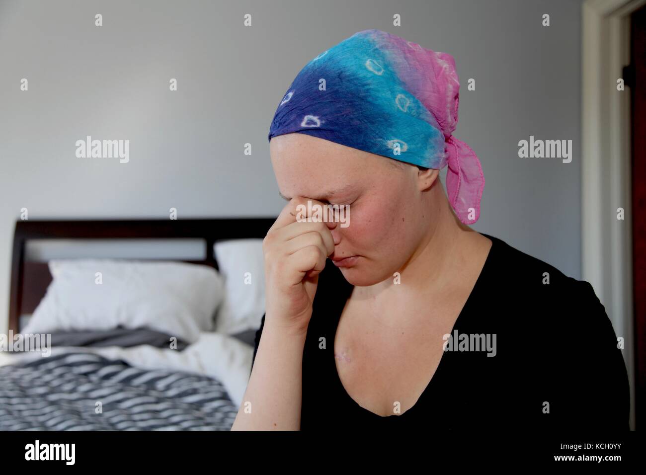 Young cancer patient in a headscarf holds head in hands with stress Stock Photo
