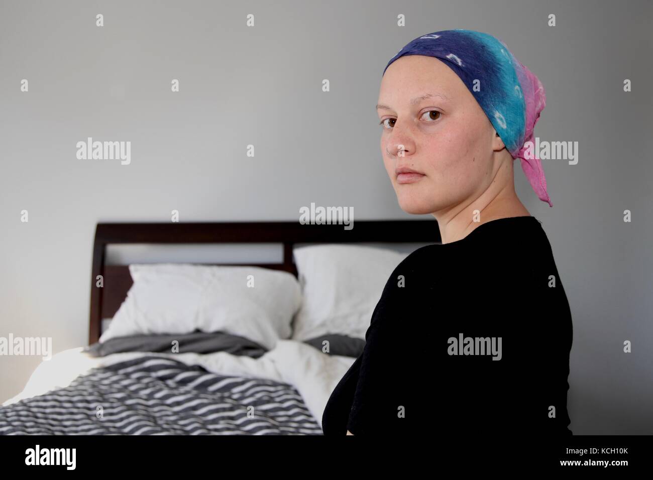 Young cancer patient in a headscarf looks at camera Stock Photo