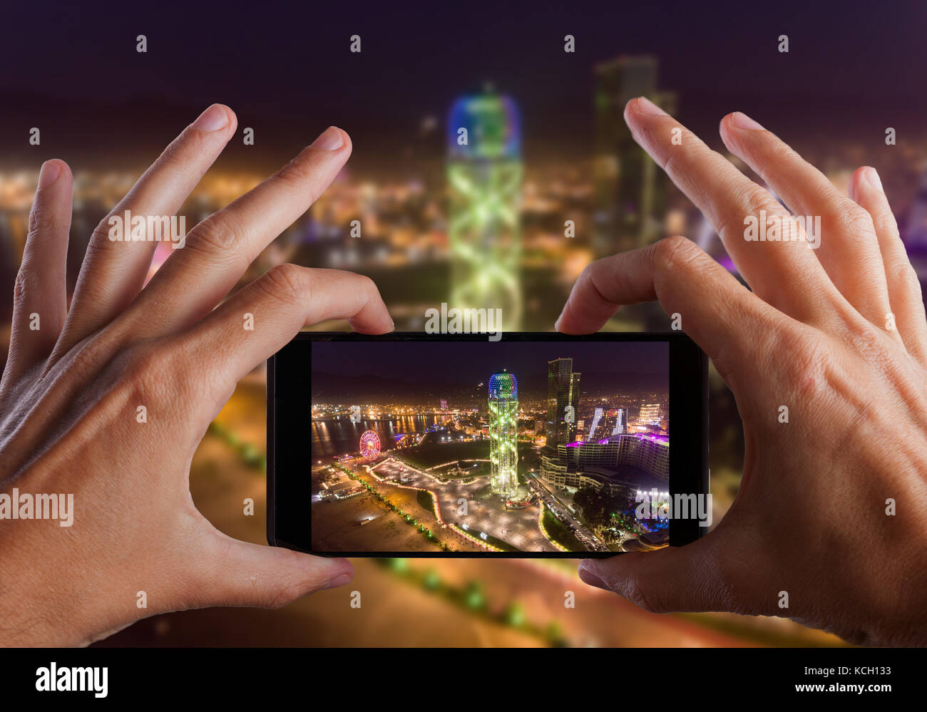 Travel concept. Hands making photo of night Batumi City, Georgia Stock Photo