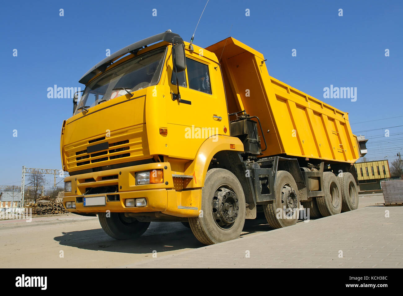 Yellow dump truck parked against clear blue sky Stock Photo - Alamy