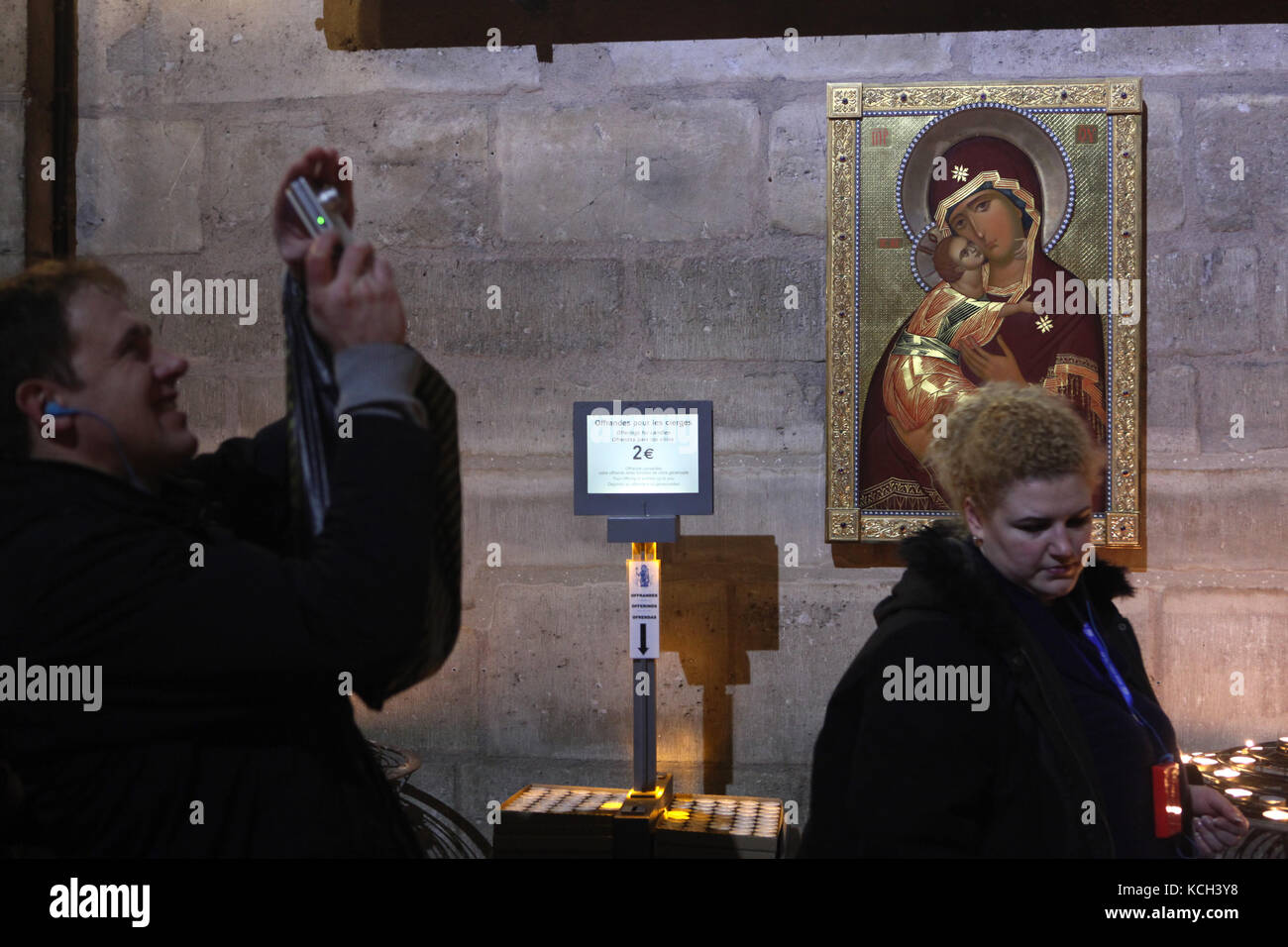 Visitors in front of the icon of the Theotokos of Vladimir in the Notre-Dame Cathedral (Notre-Dame de Paris) in Paris, France. The copy of the Byzantine icon regarded as the holy protectress of Russia was gifted to the Notre-Dame Cathedral by Patriarch Alexius II of Moscow, the primate of the Russian Orthodox Church. Stock Photo