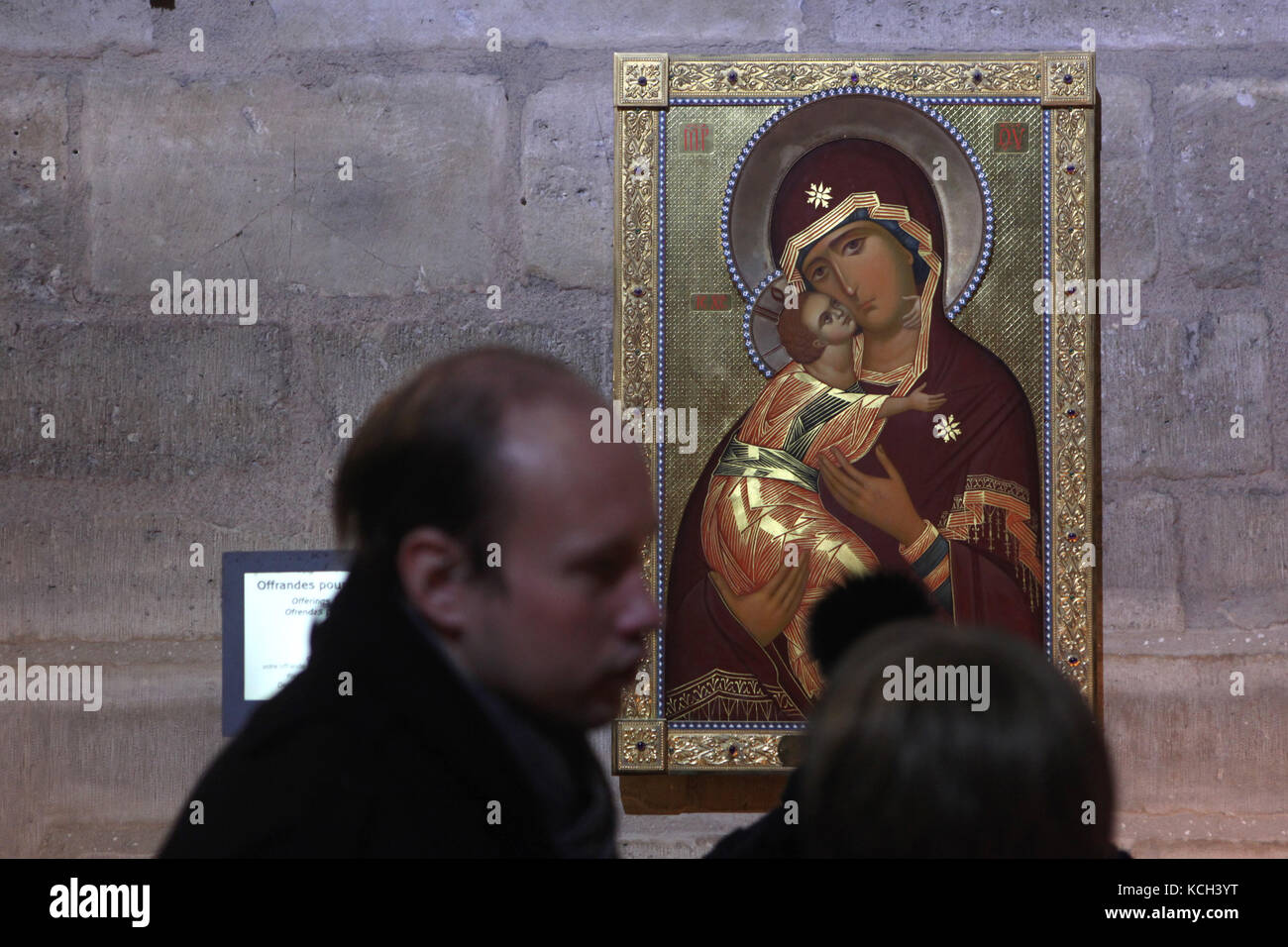 Visitors in front of the icon of the Theotokos of Vladimir in the Notre-Dame Cathedral (Notre-Dame de Paris) in Paris, France. The copy of the Byzantine icon regarded as the holy protectress of Russia was gifted to the Notre-Dame Cathedral by Patriarch Alexius II of Moscow, the primate of the Russian Orthodox Church. Stock Photo