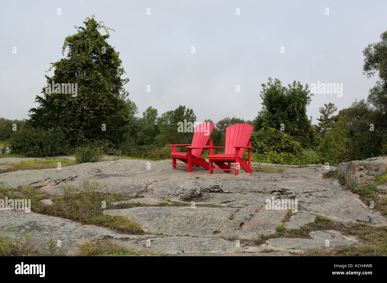 Two red Adirondack chairs on a granite hill in a park Stock Photo Alamy