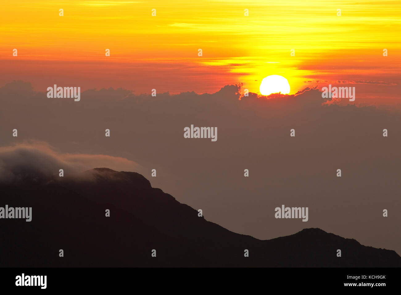 Sun rising above clouds, Haleakala National Park, Maui, Hawaii Stock