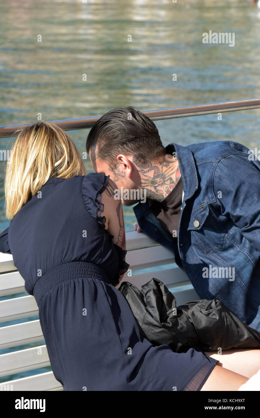 A young couple leaning over the side of a boat together. Young lovers on a boat trip in Greece. Heavily tattooed man and woman. Stock Photo
