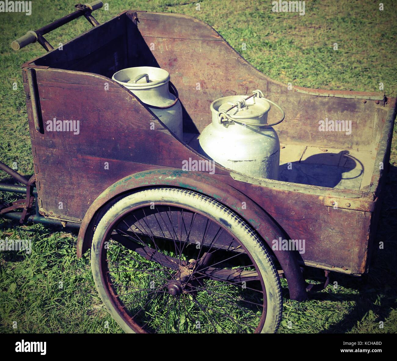 two old milk cans transported with an old wagon and vintage bicycle Stock Photo