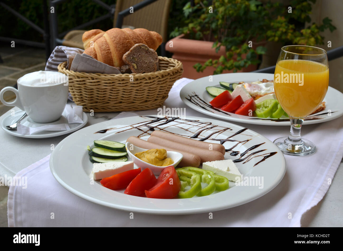 Table with nicely served  American breakfast - sausages, vegetables, croissants Stock Photo