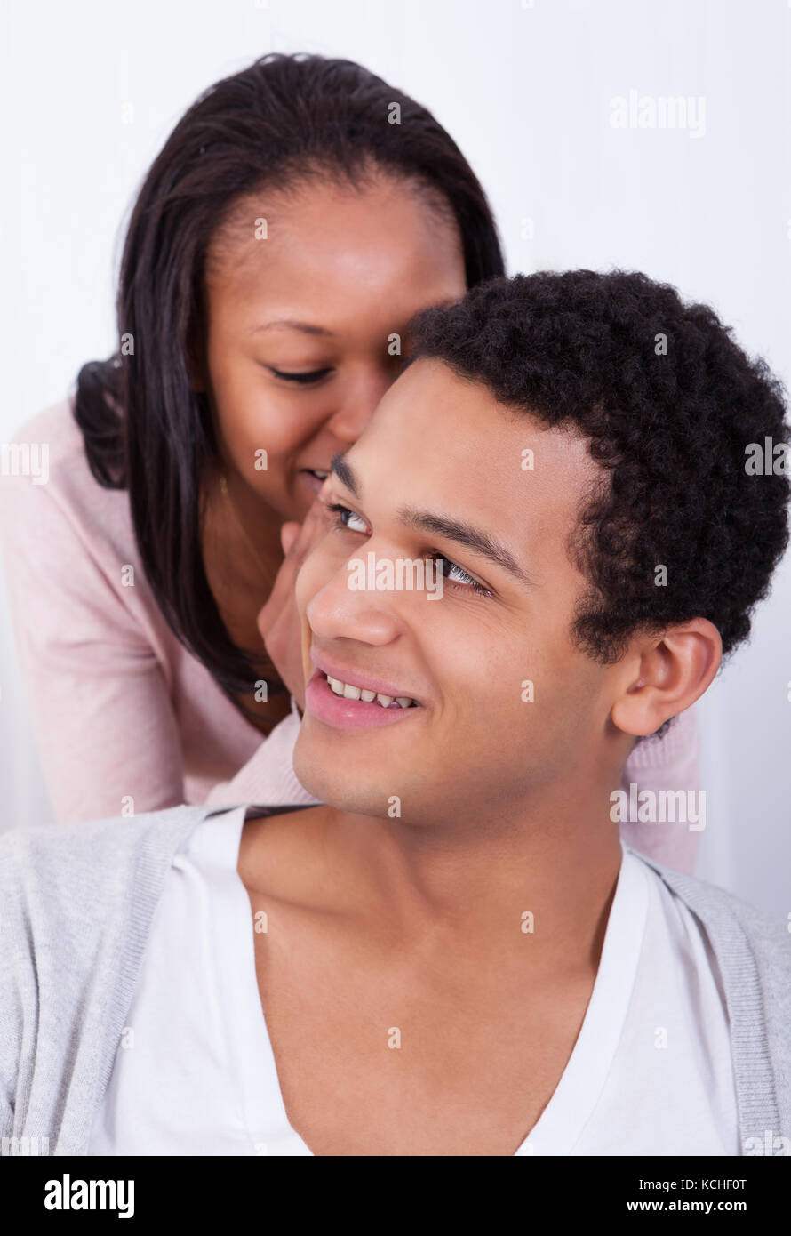 Portrait Of Woman Whispering To Boyfriend's Ear Stock Photo