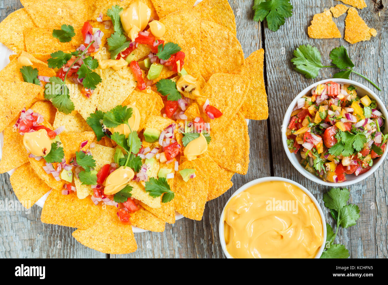 Yellow corn chips nachos with cheese sauce and salsa sauce. Mexican food snack concept. Stock Photo