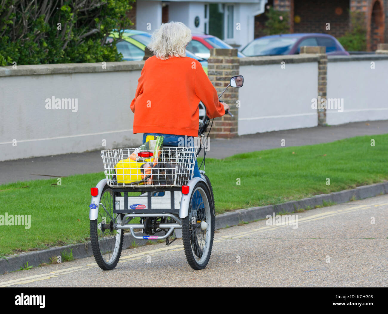 Elderly woman riding a Powabyke electrically powered tricycle, on the road in the UK. Stock Photo