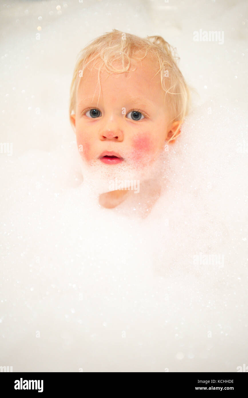 A young boy taking a bubble bath covered by bubbles Stock Photo