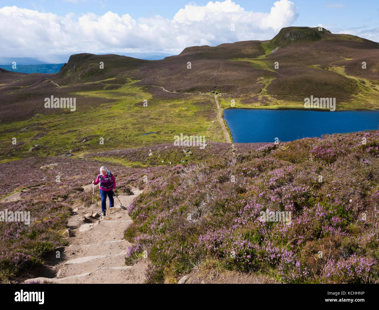 A female walker climbing Ben Vrackie, a hill outside the Perthshire town of Pitlochry. Loch a'Choire can be seen below. Stock Photo