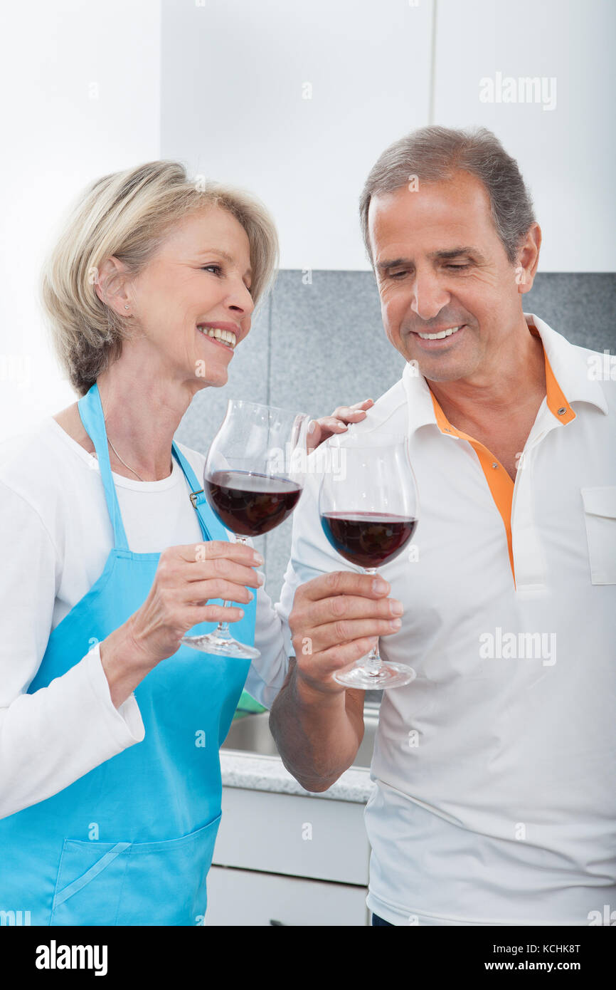 Happy Mature Toasting Glass Of Wine In Kitchen Stock Photo - Alamy