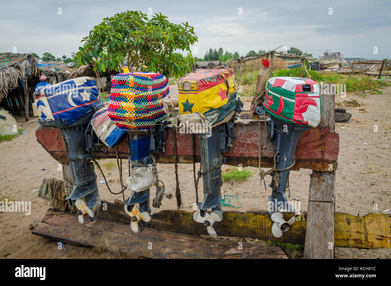 Colorful lined up fishing boat engines with artistic covers on wooden stand, The Gambia, West Africa Stock Photo