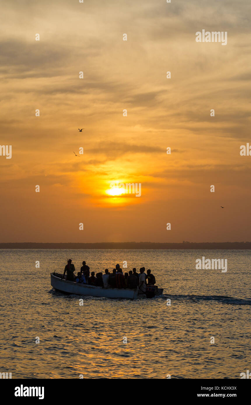 Wooden boat with unidentifiable people and beautiful sunset over sea, Bubaque, Bijagos islands, Guinea Bissau, Africa Stock Photo
