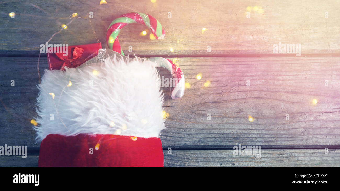 Wrapped gift box and candy cane in stocking against wooden wall during ...