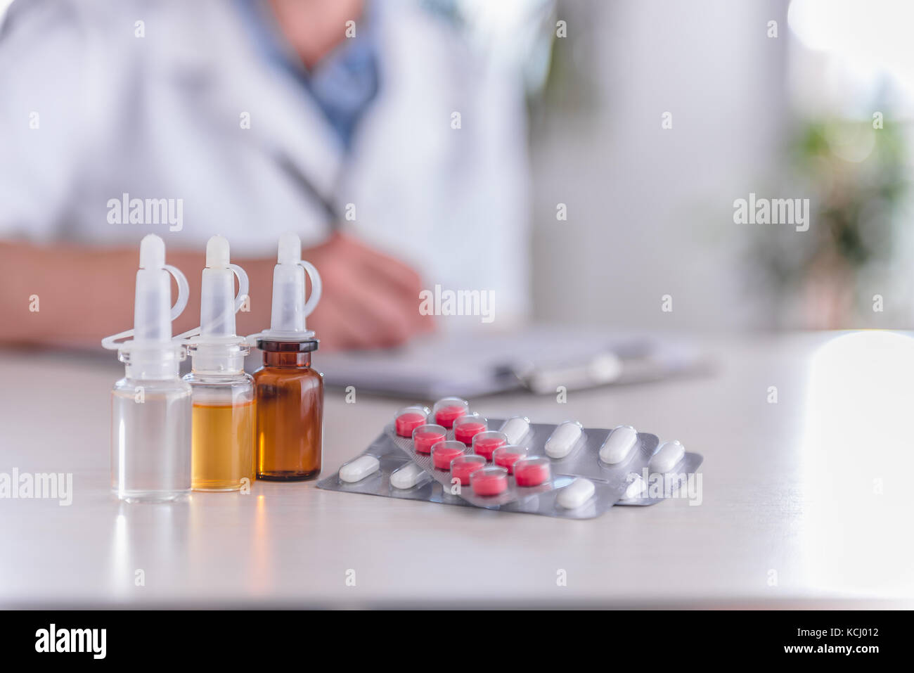 Medical supplies on table and doctor in the background writing prescription Stock Photo