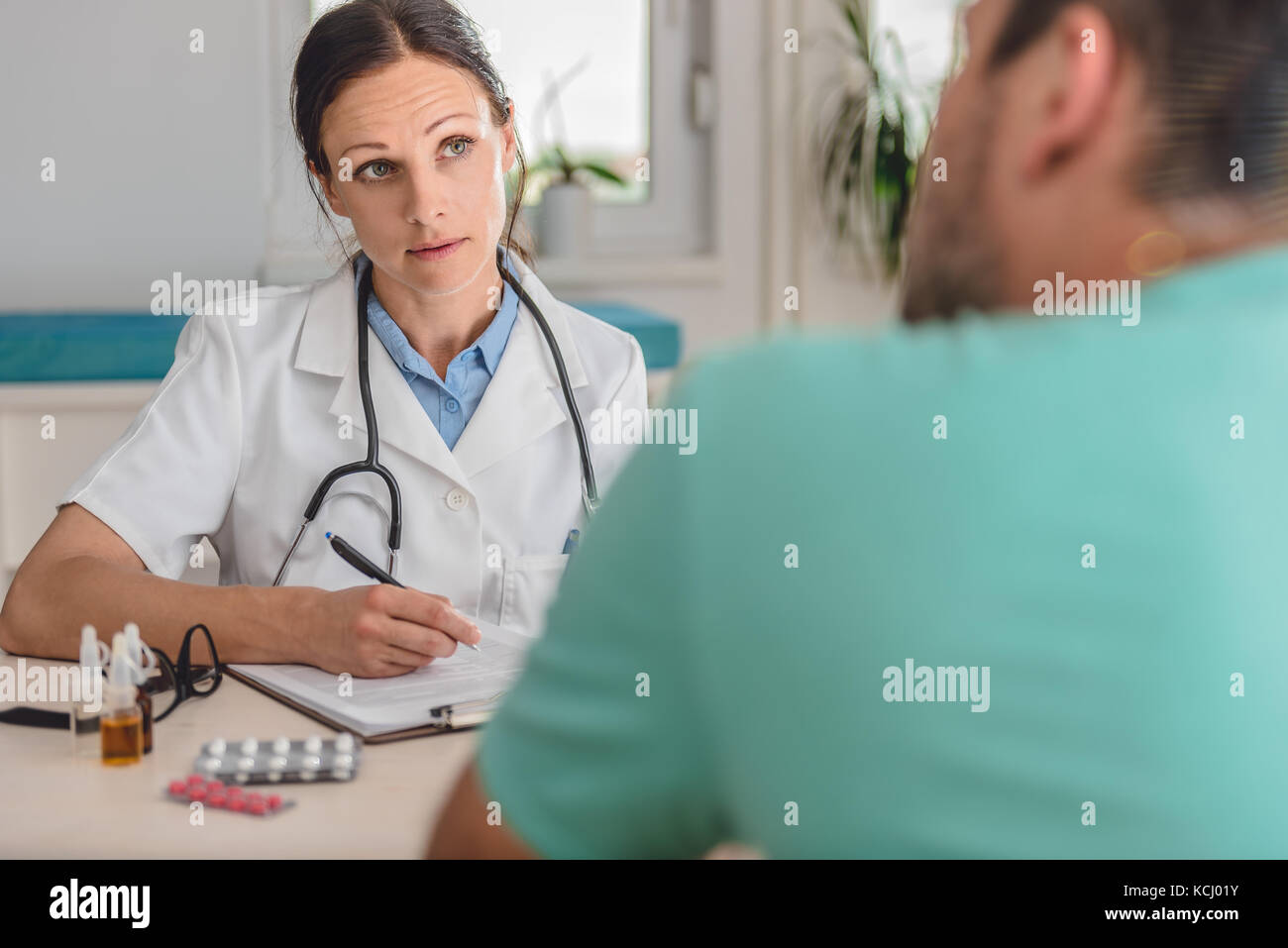 Doctor writing a prescription to patient Stock Photo