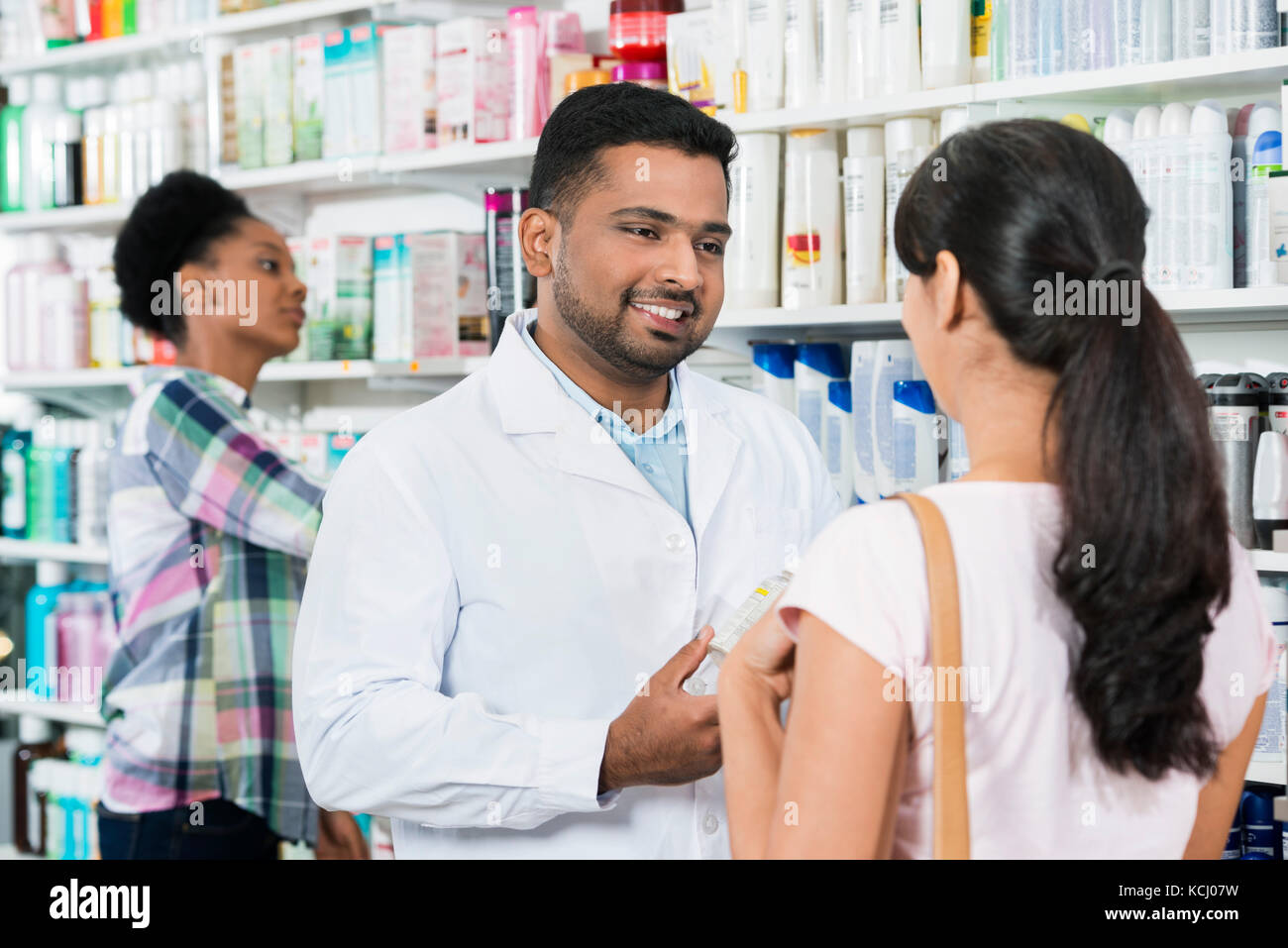 Young Chemist Assisting Female Customer Stock Photo