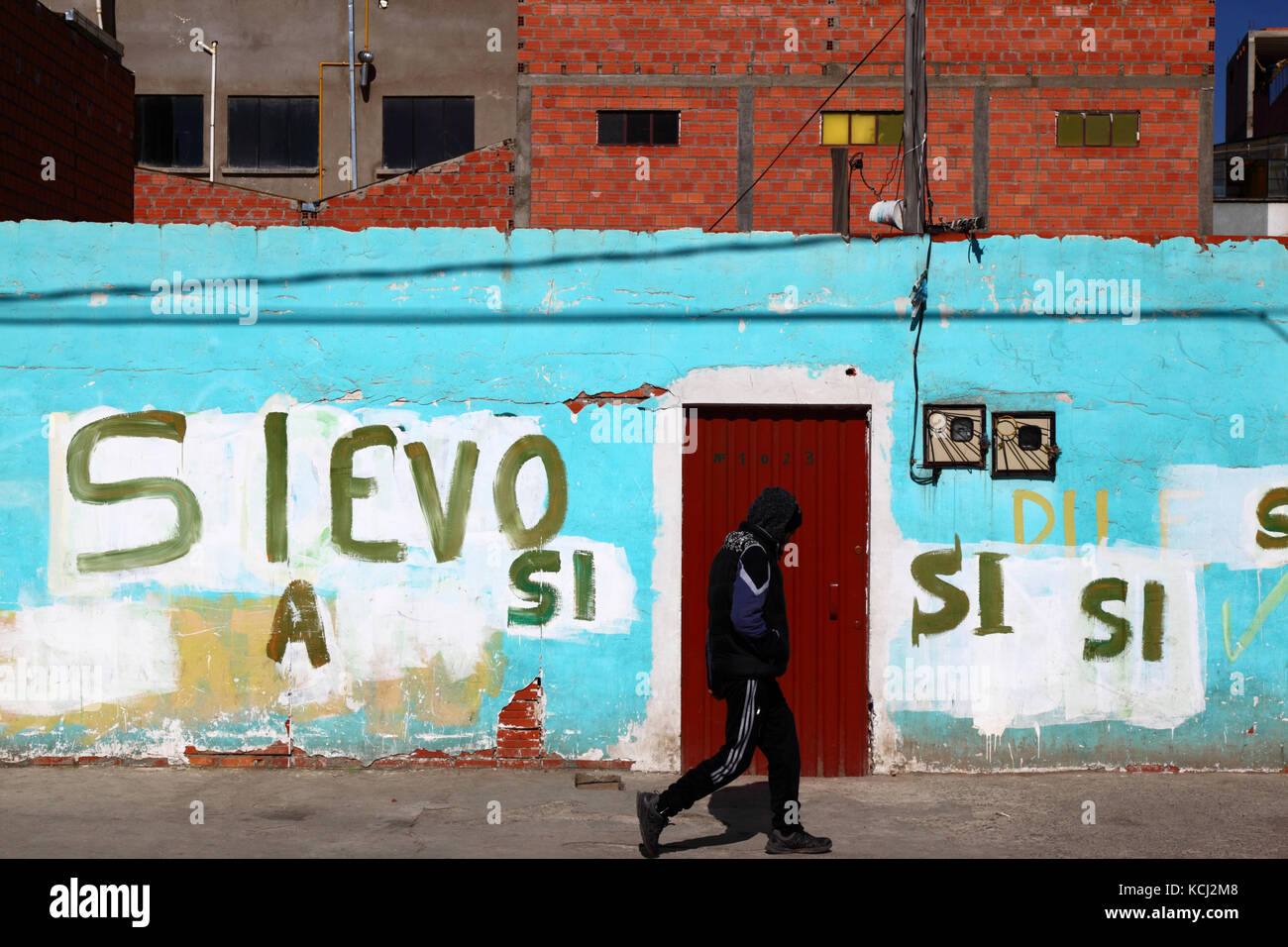 Man walking past graffiti showing support for Bolivian president Evo Morales, El Alto, Bolivia Stock Photo