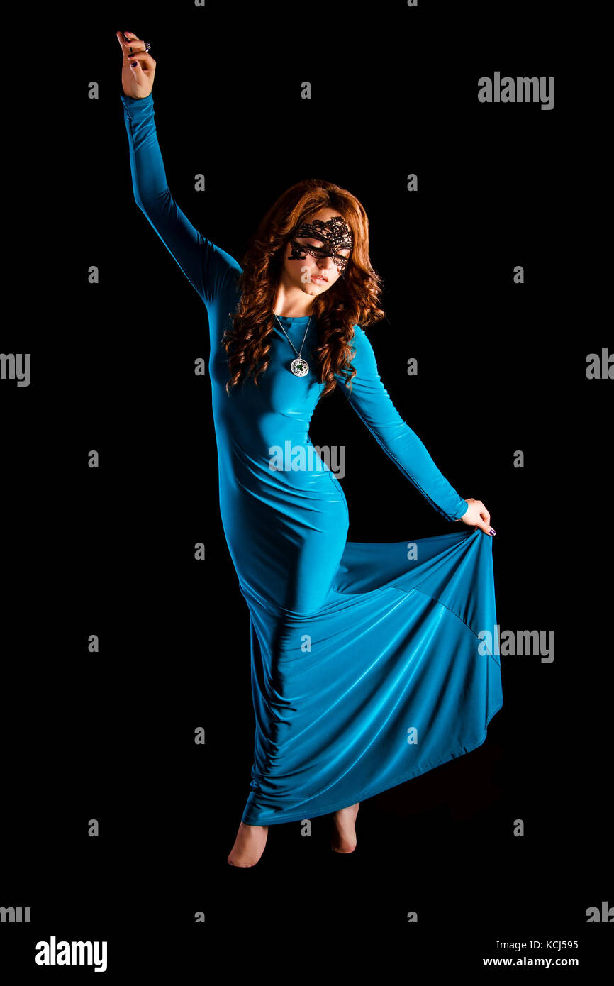 Gorgeous young lady dancing in a long green evening dress over black background Stock Photo