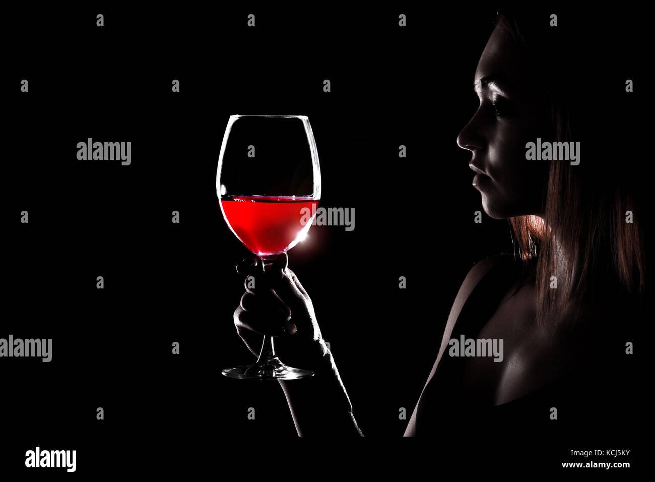 Beautiful young woman holding the glass of a red wine in darkness Stock ...