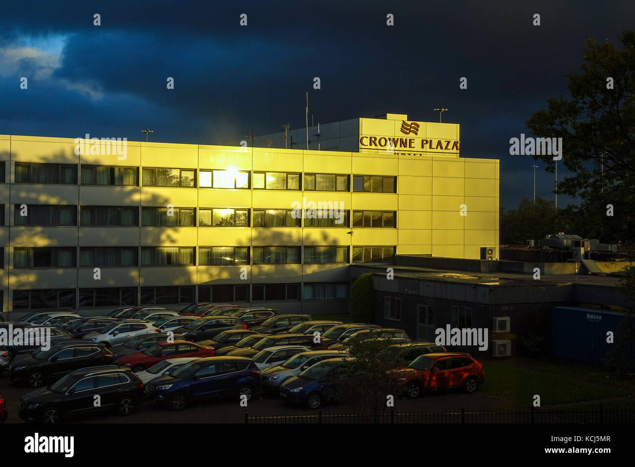 Crowne Plaza Hotel at Manchester airport with evening sunshine and dark sky behind Stock Photo