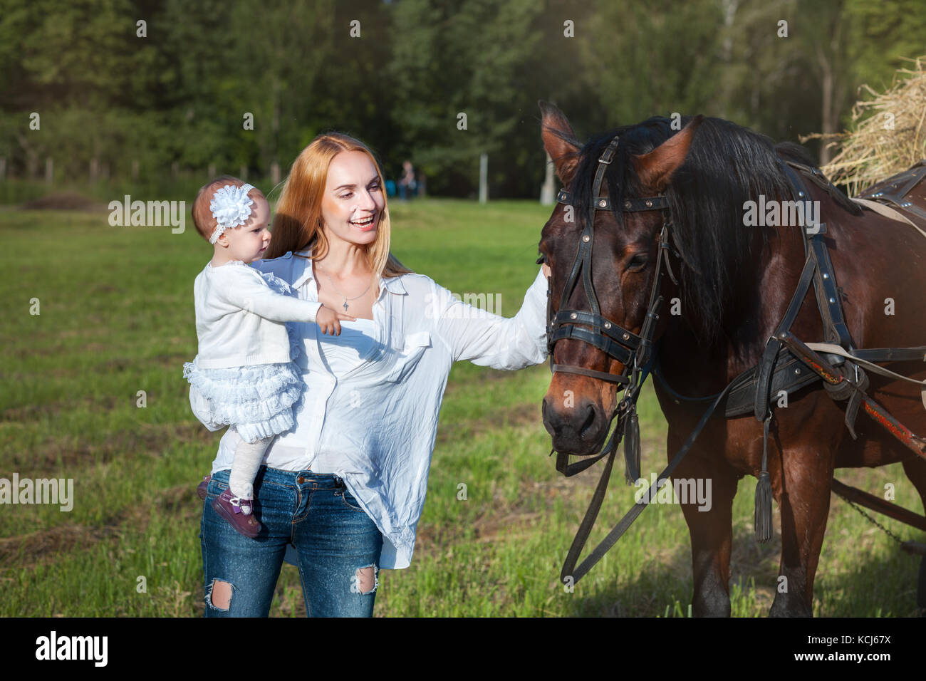 Young mother and child near a horse. Mother stroking a horse and smiling Stock Photo