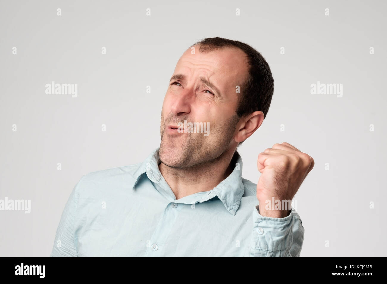 Happy lucky mature hispanic male winner exclaiming, rejoicing at his success at work, saying yes, clenching fist and closing eyes Stock Photo