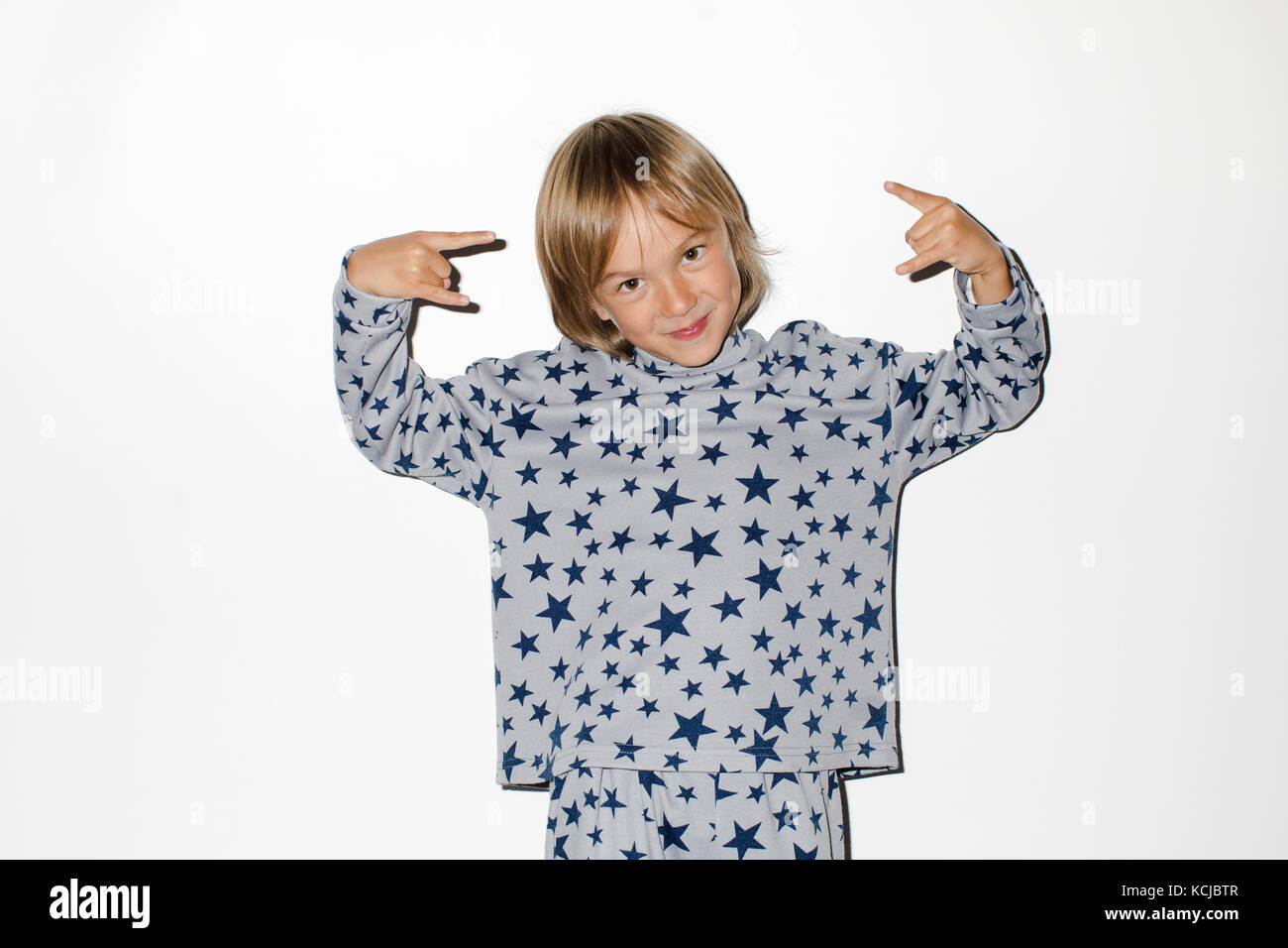 Cute boy gesturing rock at camera on a white background Stock Photo