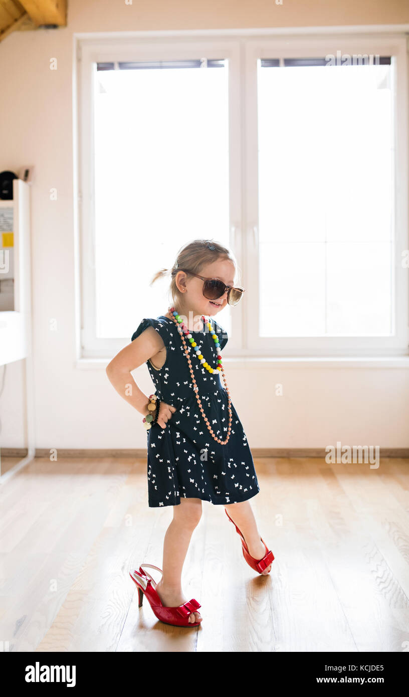 Cute little girl in dress and red high heels at home Stock Photo - Alamy