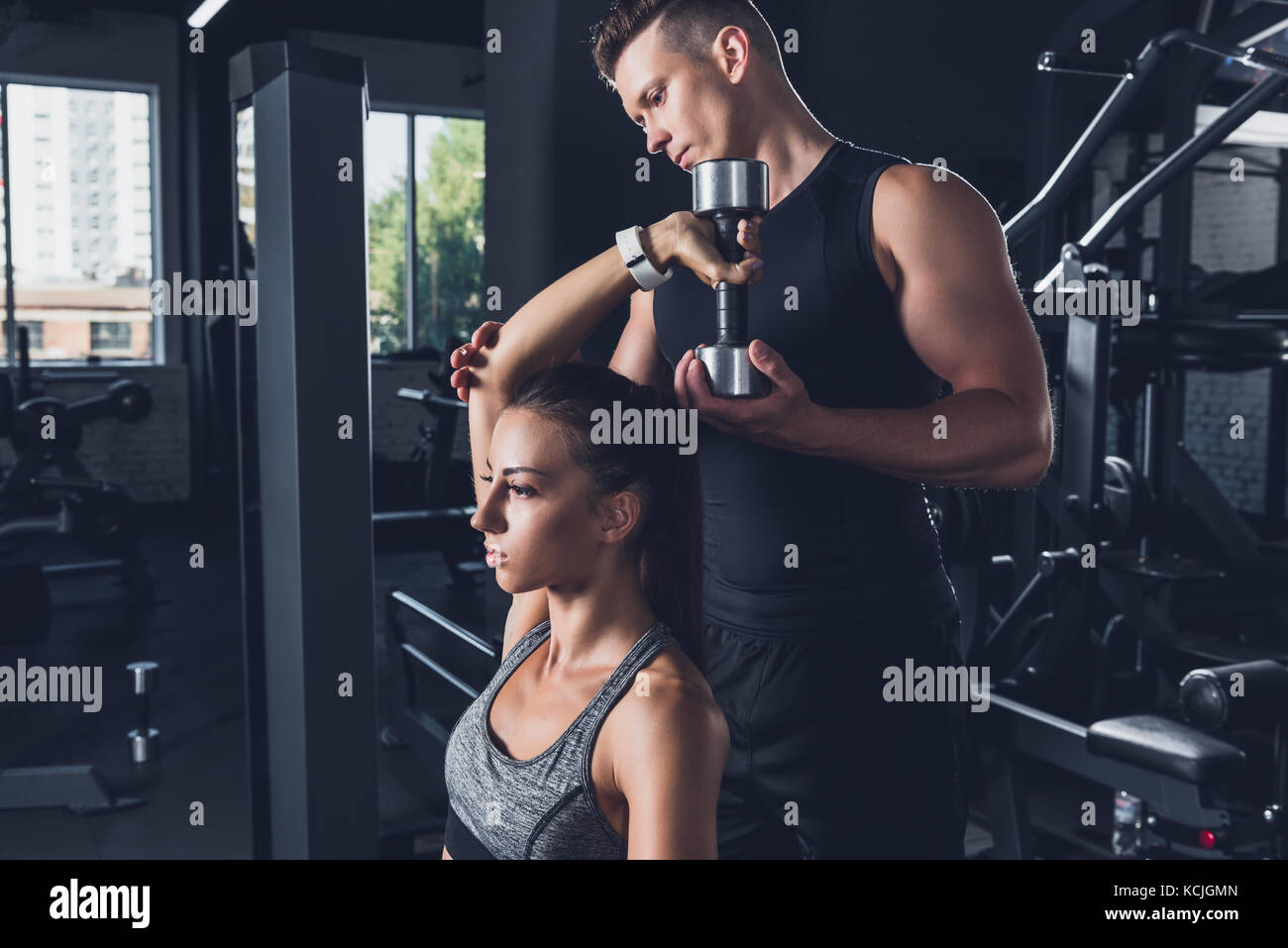 trainer helping woman to exercise with dumbbell Stock Photo - Alamy