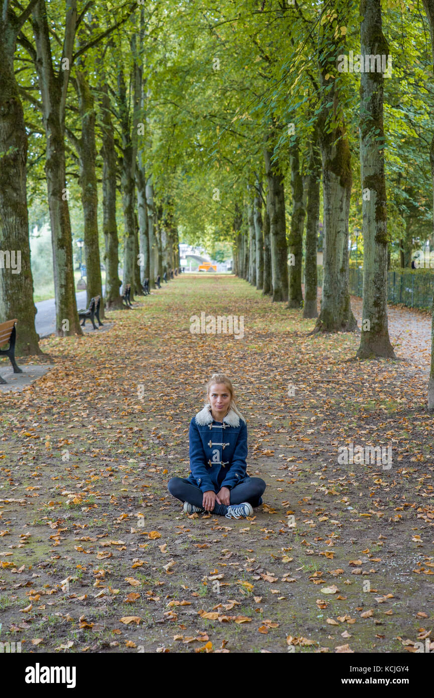 Blonde girl sitting on the floor between the trees Stock Photo - Alamy