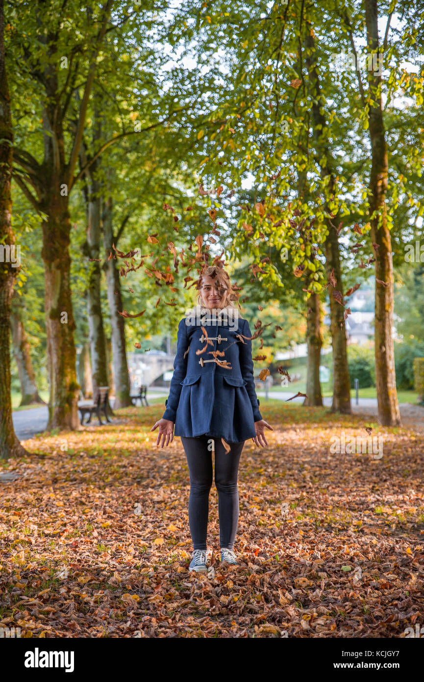 Blonde girl throwing yellow leaves, Luxembourg Stock Photo