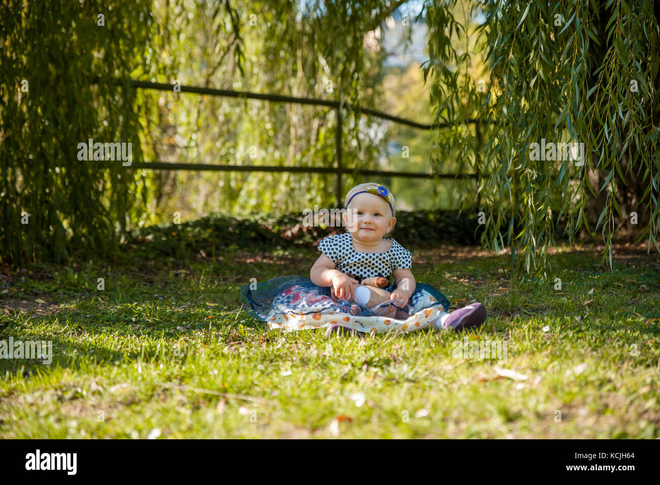 Baby girl sitting on the grass and playing with her teddy bear Stock ...