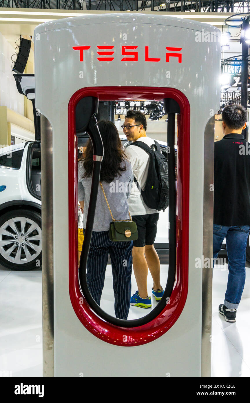 Tesla charger framing husband and wife at 2017 Shenzhen Auto Show. Stock Photo