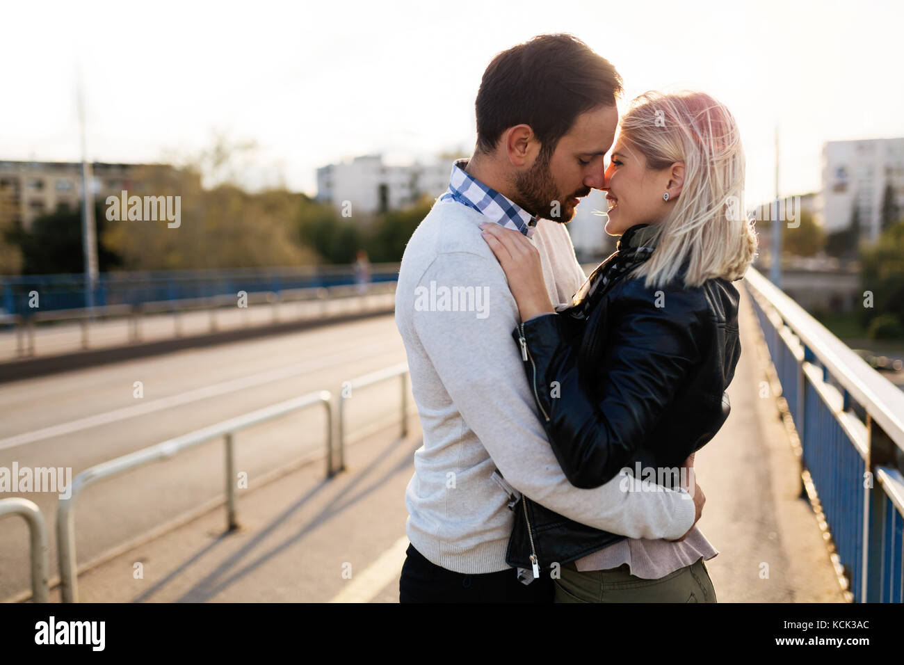 Happy young couple hugging and kissing on bridge Stock Photo - Alamy