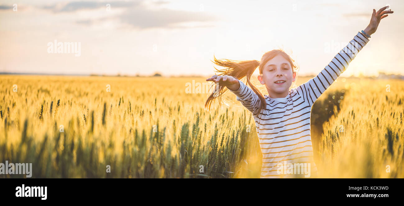 Little girl running cross the wheat field at sunset Stock Photo