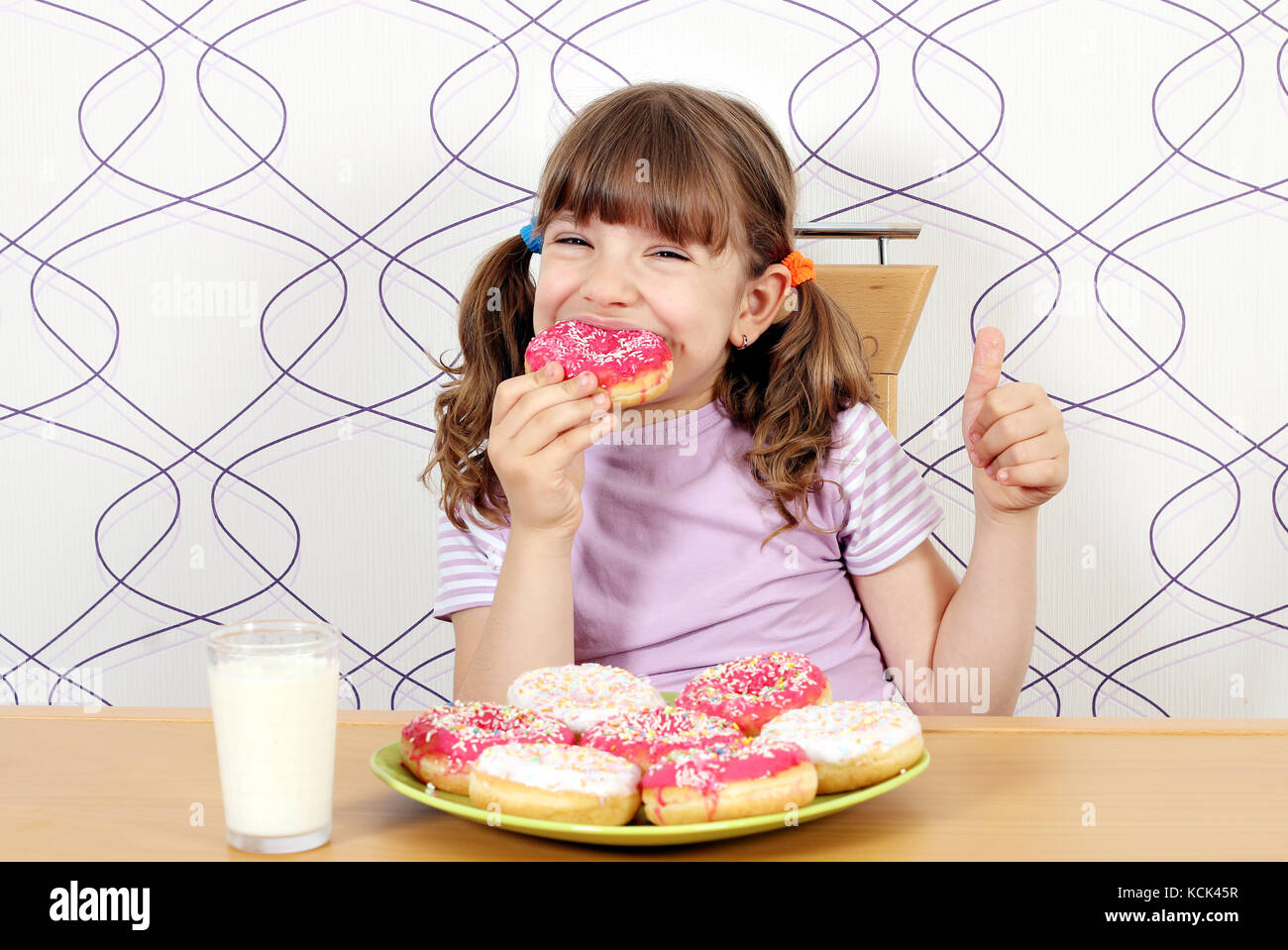 hungry little girl eat donuts Stock Photo