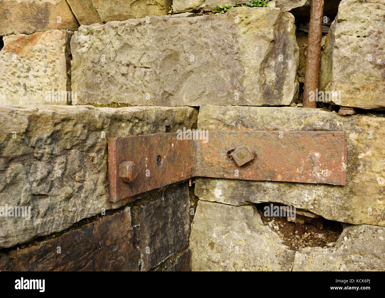 Rusty Wrought iron bracket and rod fixed to stonework with rusty bolts in burrs country park bury lancashire uk Stock Photo
