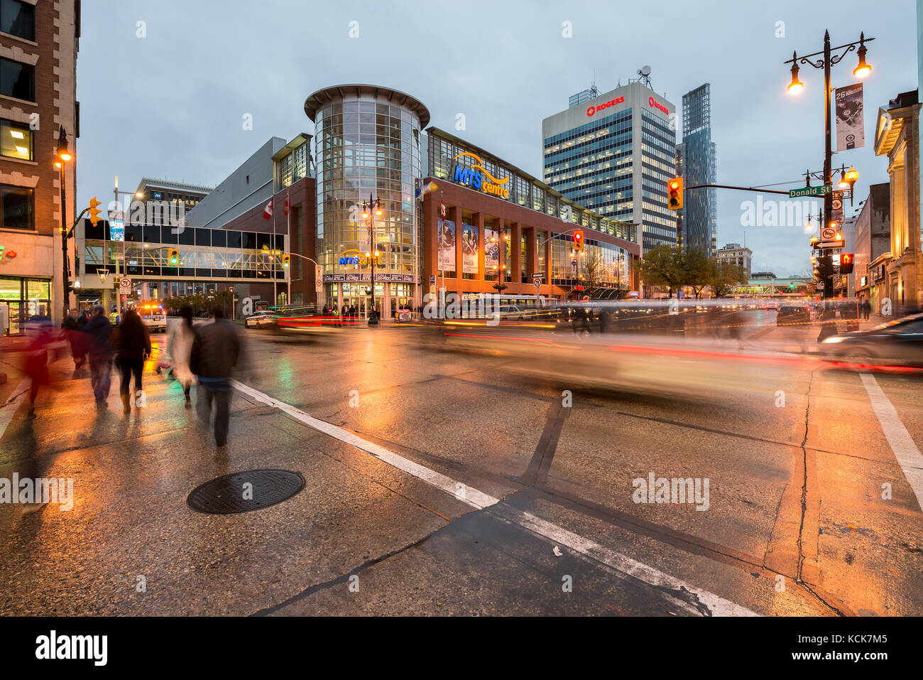 People crossing Portage Avenue in front of MTS Centre at dusk downtown Winnipeg in Manitoba, Canada Stock Photo