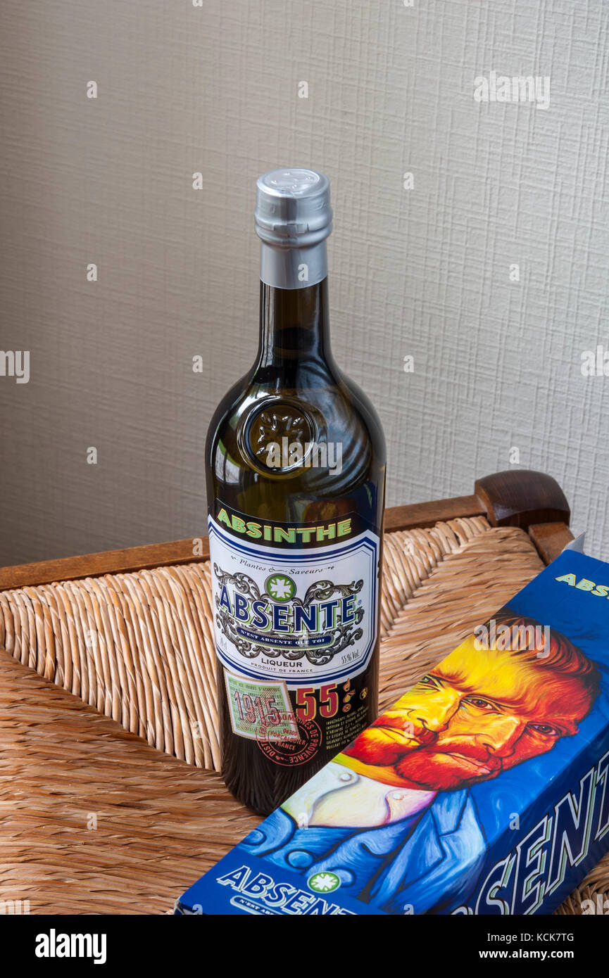 Absinthe bottle and ‘Van Gogh’ illustrated bottle box on rustic straw chair seat Stock Photo